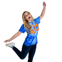 A person posing with a blue tie-dye t-shirt featuring a yellow crown logo.
